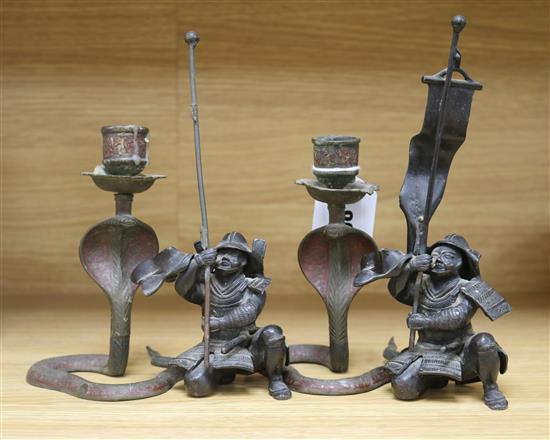 A pair of Japanese bronzed spelter figures of kneeling samurai and a pair of Indian cobra candlesticks